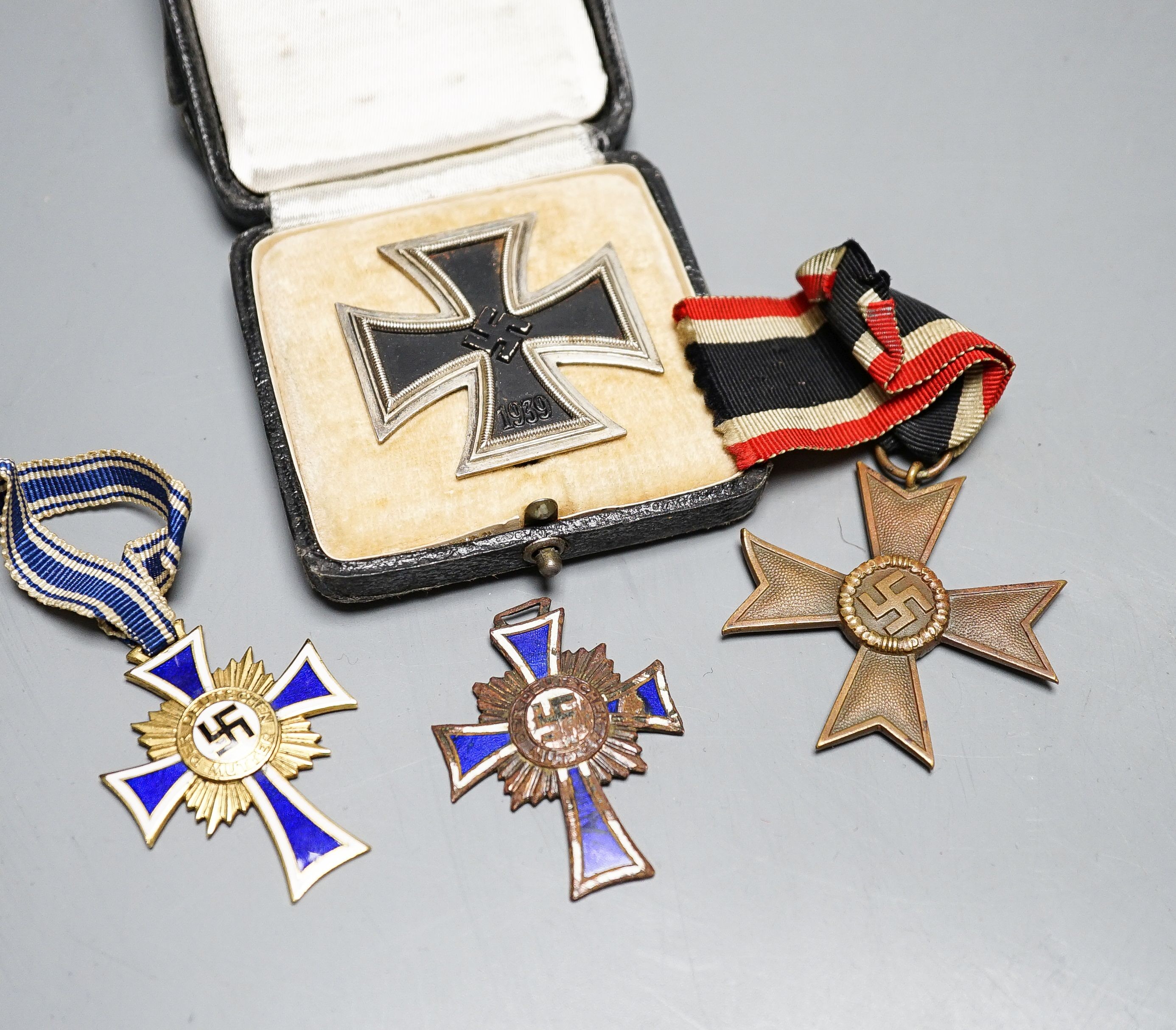 WWII Third Reich medals to include a Cross of Honour of the German Mother in gilt, another damaged in bronze, War Merit Cross (without swords), a 1939 Iron Cross and a Third Reich cuff link (5)